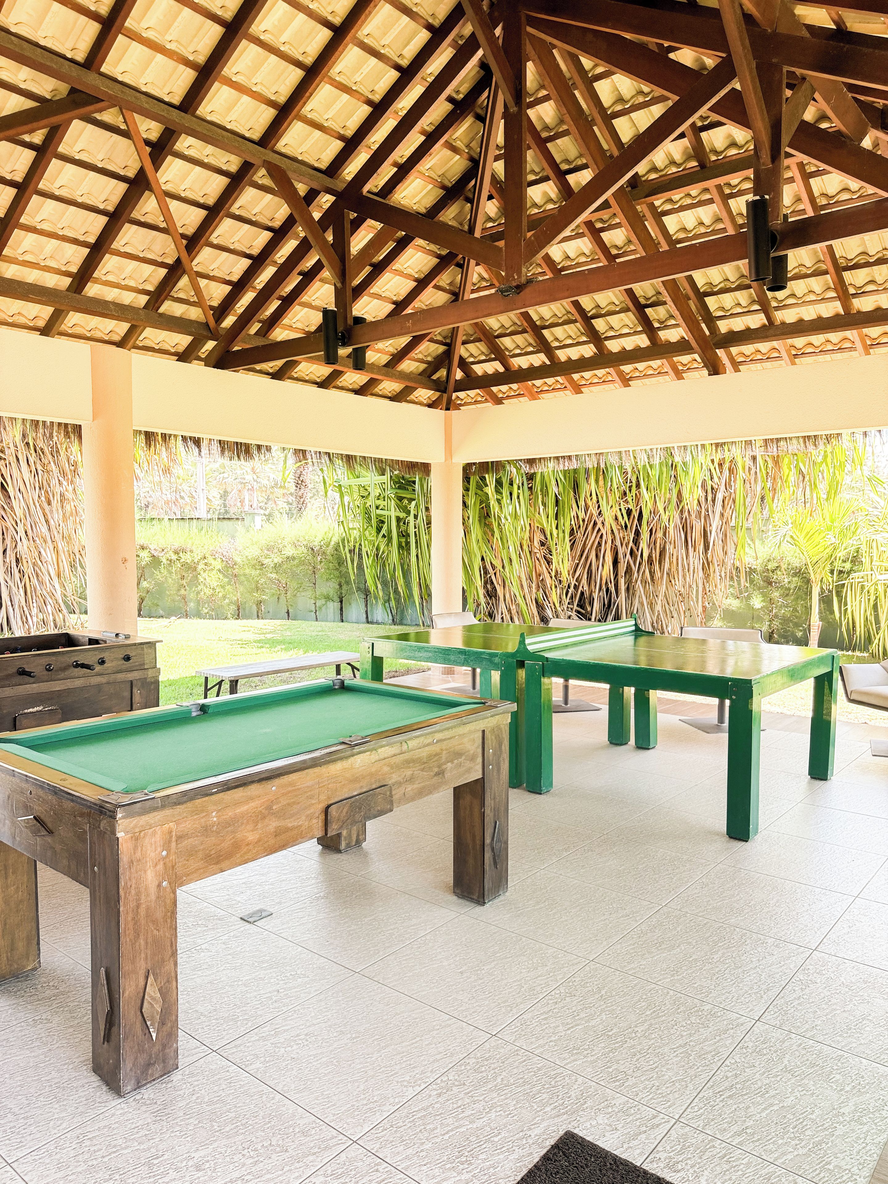 Ein Innenbereich mit Freizeitaktivitäten, darunter ein Billardtisch, ein Snookertisch und eine Lounge mit Blick auf einen Garten.