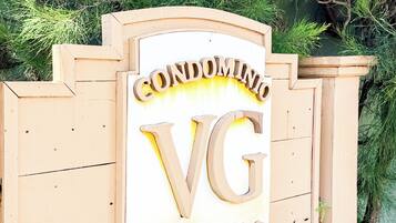 Ein Holzschild mit der Aufschrift 'CONDOMINIO VG', das ein Apartmenthaus kennzeichnet.