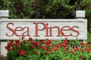 A wooden sign with the text "Sea Pines" surrounded by red flowers. - Bamboo-Lined Back Deck & Patio w/ Fire Pit; Dog-Friendly; Community Pool, Pickleball & Playground (Hilton Head Island)