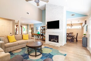 A living room with a sofa, coffee table, fireplace, TV, and dining area. - Bamboo-Lined Back Deck & Patio w/ Fire Pit; Dog-Friendly; Community Pool, Pickleball & Playground (Hilton Head Island)