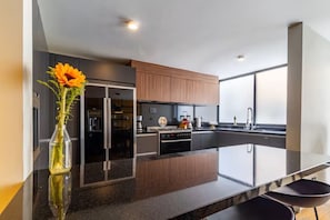 A modern kitchen with a large island, dark cabinetry, and a vase with flowers. - Casa Mezcal | Stylish 8-guest stay in Roma Sur (Ciudad de México)