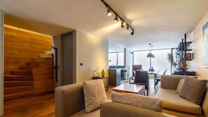 Een moderne woonkamer met een bank, een eettafel en een trap naar een andere kamer.