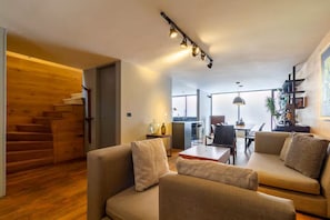 A modern living room with a sofa, a dining table, and a staircase leading to another room. - Casa Mezcal | Stylish 8-guest stay in Roma Sur (Ciudad de México)