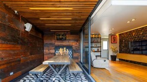 Een modern interieur met houten plafond, vloer met geometrisch patroon, een houten bank en een glazen scheidingswand.