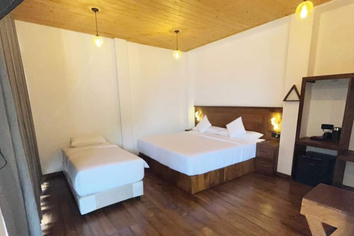 A bedroom with two beds, wooden flooring, and pendant lights.