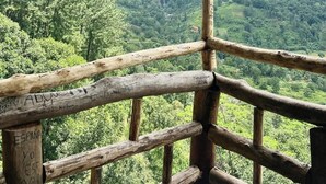 Una estructura de madera con vistas a un valle verde exuberante y montañas distantes.