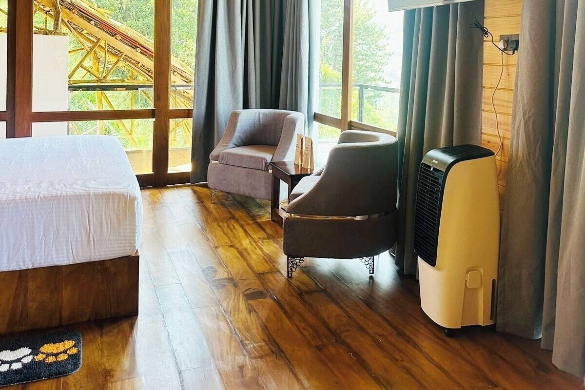 A room with a bed, two chairs, a TV, and an air conditioner.