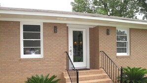 A single-story brick house with a front door, a small porch, and a set of stairs leading to the door. - Lake Murray home with boat ramp, dock, panoramic views close to USC@Columbia. (Chapin)