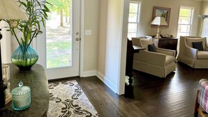A living room with a door leading to a patio, a sofa, a lamp, and a vase with plants. - Lake Murray home with boat ramp, dock, panoramic views close to USC@Columbia. (Chapin)