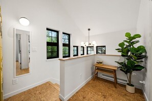 Ein Flur mit einer hölzernen Bank, einer Topfpflanze und einem Spiegel an der Wand.