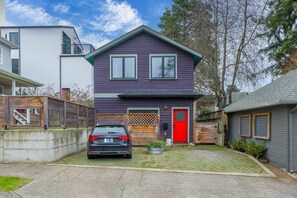 Ein zweistöckiges Haus mit roter Tür, einer Garage und einem Auto auf der Auffahrt.