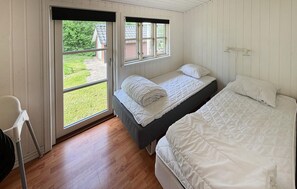 Une chambre avec deux lits, une fenêtre et une vue sur l’extérieur.
