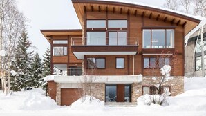 A modern two-story house with a stone facade, large windows, and a balcony.