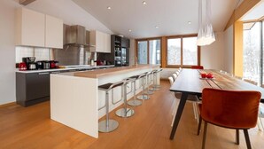 A modern kitchen with a central island, bar stools, and a dining table with chairs.