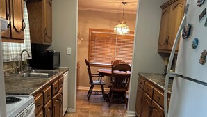 A kitchen with wooden cabinets, a dining table, and a refrigerator. - Fabulous 3-bedroom house in charming Oxford (Oxford)