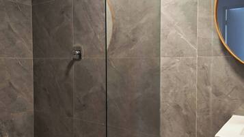 Une salle de bain moderne avec une douche à parois de verre, un meuble-lavabo en bois et un mur recouvert de carreaux de marbre.