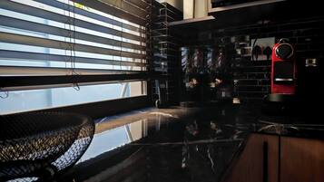 A modern kitchen with a black countertop, stainless steel appliances, and a red clock.