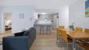 Een modern appartement met een woonkamer, een eethoek, een keuken en een klein balkon.