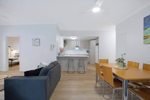 Eine moderne Wohnung mit Wohnzimmer, Essbereich, Küche und einem kleinen Balkon.