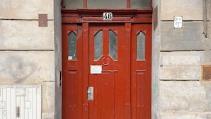 Una puerta roja con el número 46, un ventanal pequeño y un timbre.