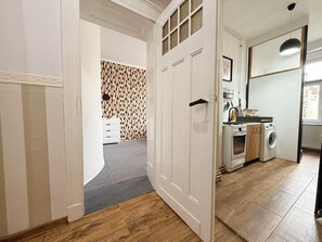 A hallway leading to a kitchen with a washing machine, a stove, and a sink. - Nowowiejska Green Point Apartment (Wrocław)