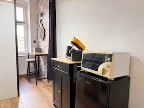 A compact kitchen with a microwave, a small refrigerator, a wooden table, and a chair. - Nowowiejska Green Point Apartment (Wrocław)