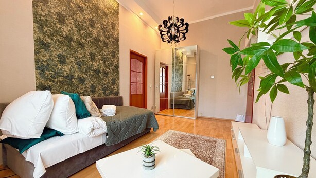 A modern bedroom with a bed, a coffee table, a potted plant, and a mirror. - Pułaskiego Spacious Apartment (Wrocław)