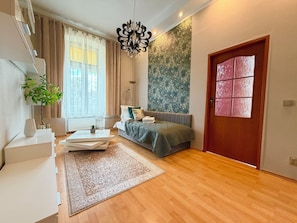 Ein modernes Schlafzimmer mit Bett, Schreibtisch, Stuhl, Pflanze und einem großen Fenster.