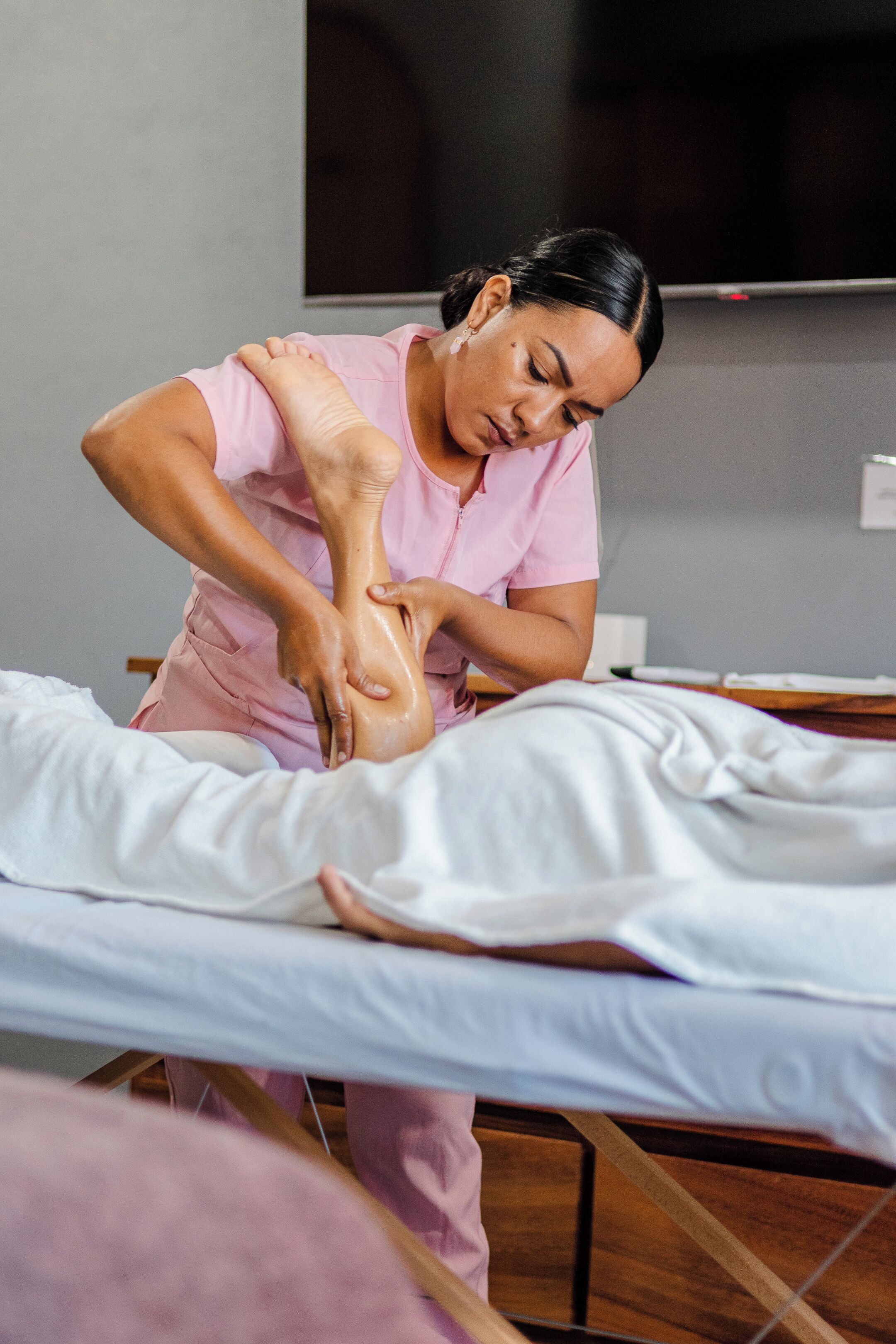 Eine Person führt Physiotherapie oder eine Massage bei einer anderen Person durch, die auf einer Liege liegt.