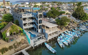 Un edificio de varios pisos llamado 'Casa Del Toro', con una piscina y barcos amarrados.