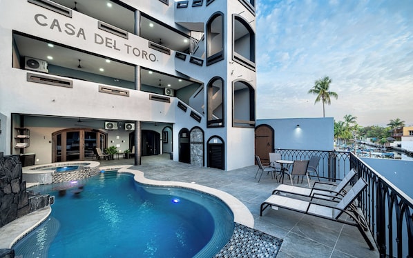 A modern hotel with a pool, outdoor seating, and a clear view of the surrounding area.
