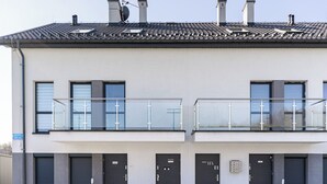 A modern building with a flat roof, two balconies with glass railings, and a series of doors. - Sikorskiego Comfort Studio #4 (Rzeszów)