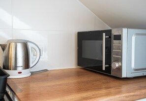A kitchenette with a microwave, a coffee maker, and a power outlet on a wooden countertop.