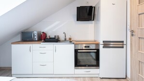 Eine kompakte Küche mit Mikrowelle, Wasserkocher, Backofen und Kühlschrank.