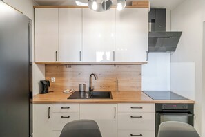 A modern kitchen with white cabinets, a wooden countertop, a stainless steel sink, and a built-in oven.