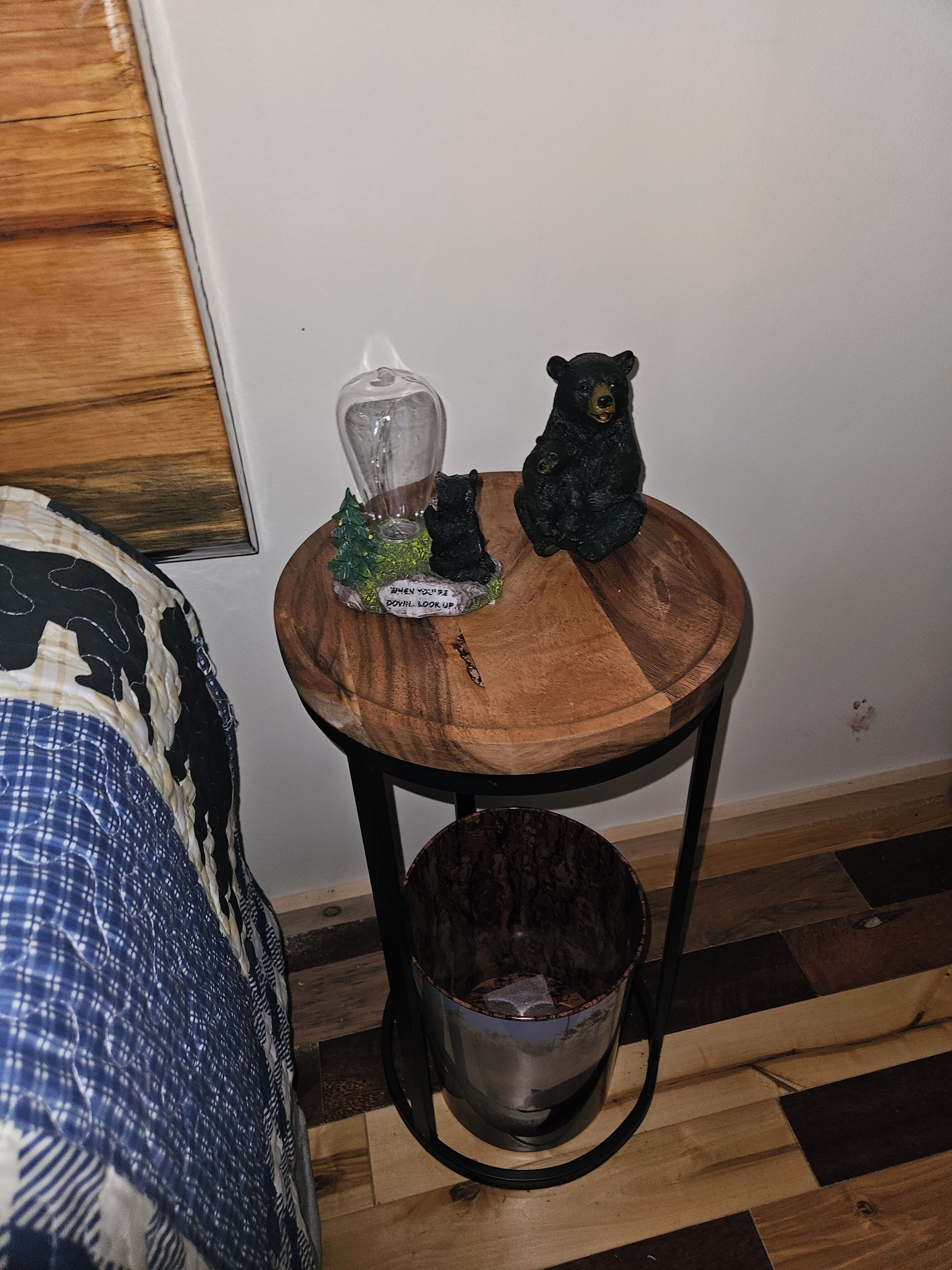 A small wooden table with a glass container and two bear figurines on top.