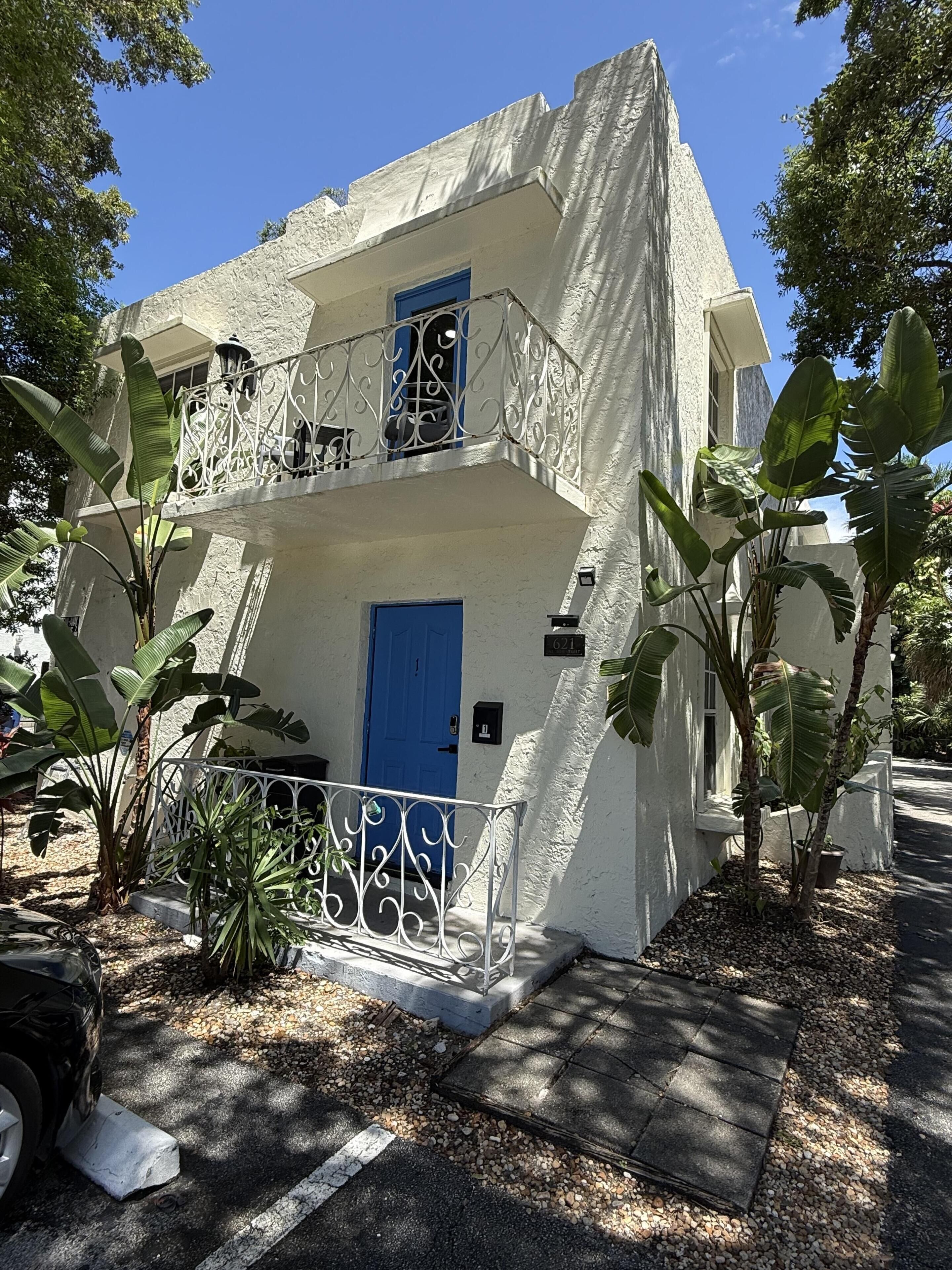 Um edifício de dois andares com porta azul e grade de varanda.