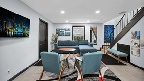 Een moderne woonkamer met een hoekbank, twee fauteuils, een salontafel en kunstwerken aan de muren.