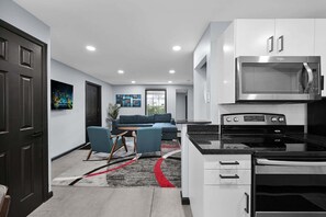 A modern kitchen with white cabinets, a stainless steel microwave, and a black stove. - Bright Designer Villa near Fort Lauderdale / Beach (Wilton Manors)