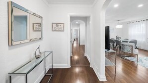 Un interno moderno con un tavolino in vetro, uno specchio e due quadri con citazioni motivazionali appesi al muro.