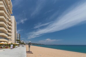 Eine Uferpromenade mit Gebäuden, einem klaren Himmel und einem Sandstrand.