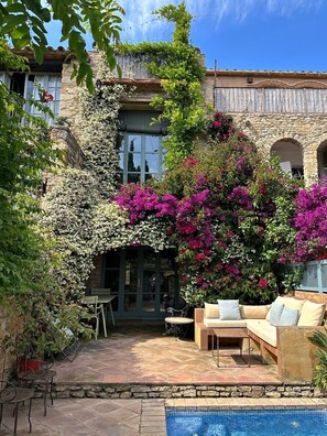 A courtyard with a pool, outdoor seating, and a stone building with arches. - ¡Vistas al Castillo! Casa con Piscina en el Centro (Peratallada)