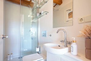 Une salle de bain moderne avec une douche à parois de verre, un lavabo blanc et un miroir au-dessus du lavabo.