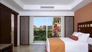 Ein Hotelzimmer mit Bett, einer Bank, einem Balkon mit Aussicht und einer Tür.