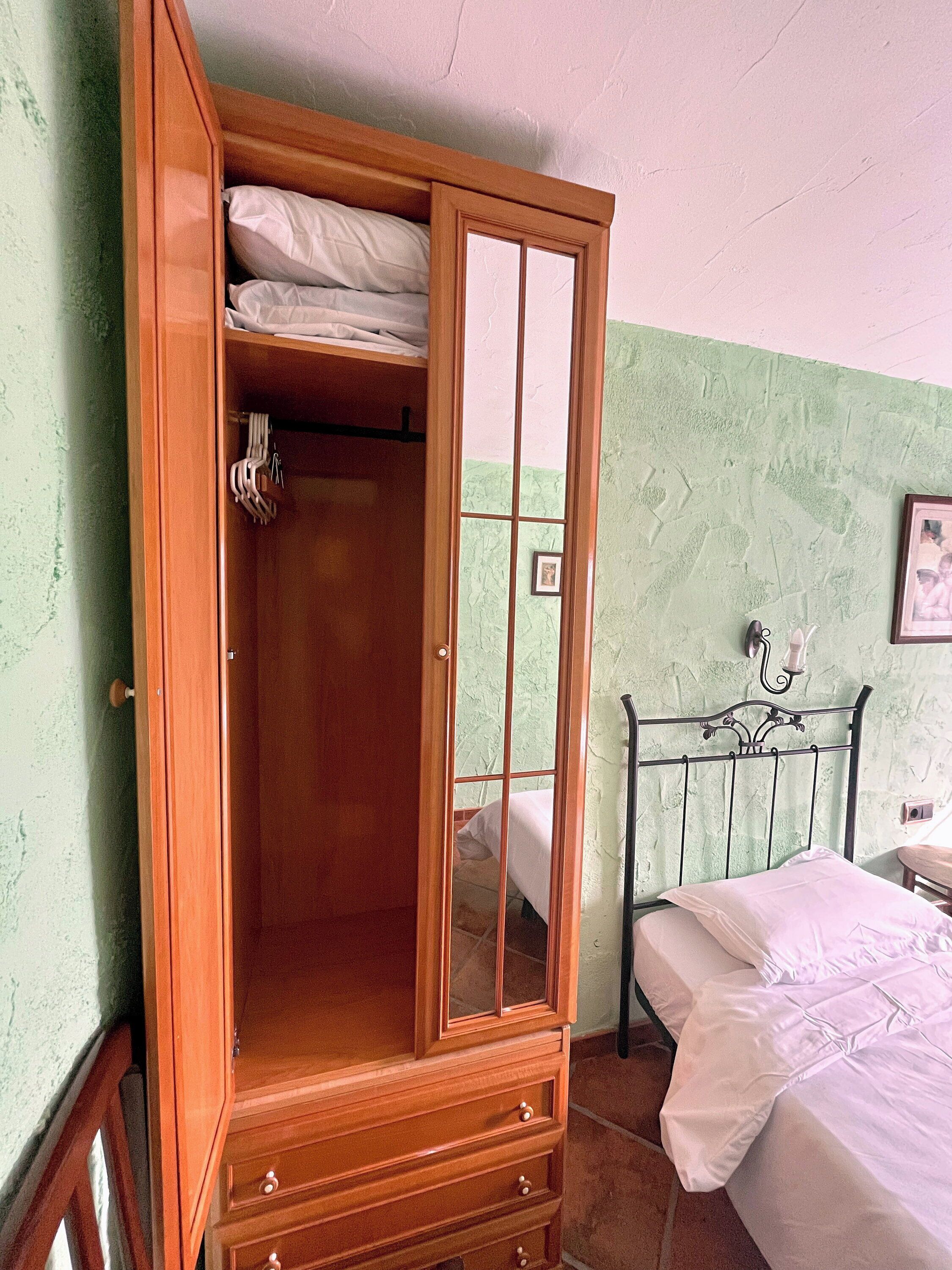 Ein Schlafzimmer mit einem Holzschrank, einem Metallbettgestell und einer Wand mit Grüner Struktur.