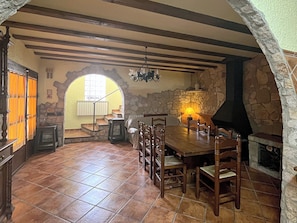 Ein Essbereich mit Steinwand, Holztisch, Stühlen und Kamin.