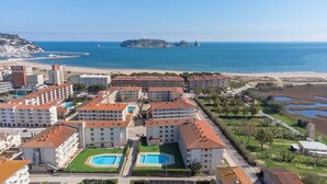Un hôtel en bord de mer, composé de plusieurs bâtiments, avec une plage et une petite île visible au loin.