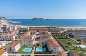 Ein Küstenhotel mit mehreren Gebäuden, einem Strand und einer kleinen Insel im Hintergrund.