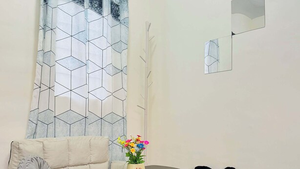 En moderne stue med en sofa, et rundt bord, en blød måtte, en pyntende plante og en unik sort stol med hjerte-design.
