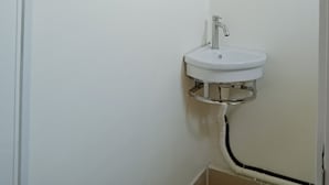Et badeværelse med en hvid vask, et sort håndklædetørrestativ og et hvidt toilet.